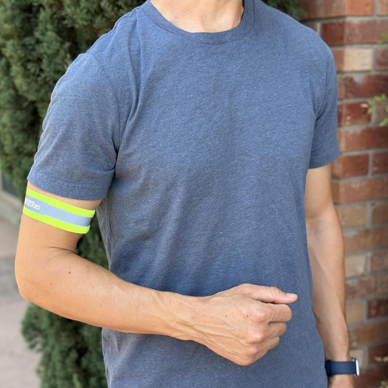 Man wearing neon yellow ReflecToes reflective arm band around upper bicep outdoors