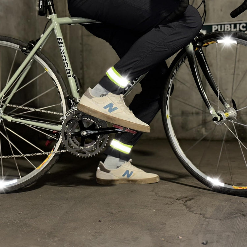 Cyclist wearing neon yellow reflective wrist band while straddling a road bike indoors