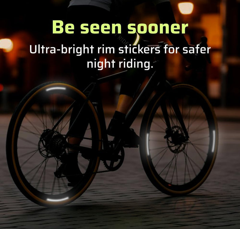 Reflective rim decals on road bike wheels glowing at night on cobblestone street