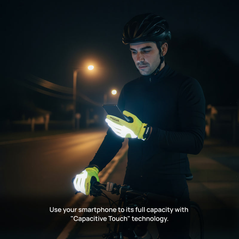 Male cyclist at night wearing neon yellow thermal winter gloves using smartphone on bike handlebars