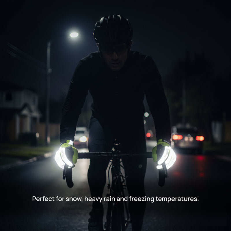 Male cyclist riding at night wearing neon yellow reflective thermal gloves on wet dark road