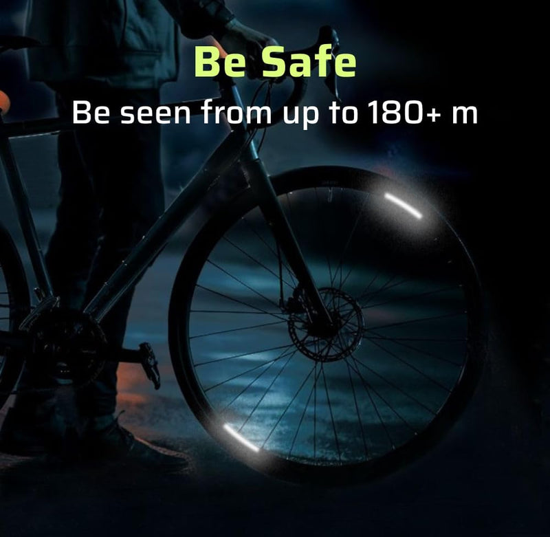 Single road bike wheel at night with reflective rim decal strips glowing under headlight